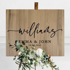 a wooden sign that says welcome to the bride and groom with flowers in front of it