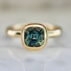 a gold ring with a green stone in the center