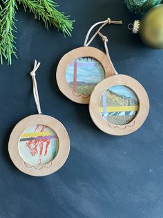 two wooden frames with pictures hanging from them on a table next to christmas ornaments and pine branches