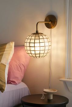 a lamp that is on the side of a bed next to a table with pillows