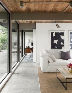 a living room with white couches and large glass doors leading to the outside patio