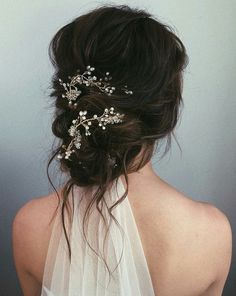 the back of a woman's head wearing a white veil with flowers on it