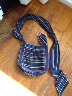 a blue and white striped bag on the floor with a tie around it's neck