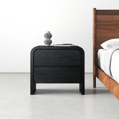 a bed sitting next to a night stand on top of a white floor