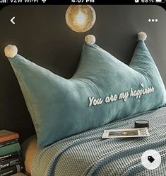 a blue pillow with pom poms on it sitting on top of a bed