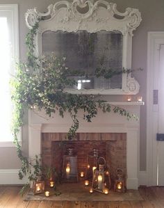 candles are lit in front of a fireplace with ivy growing on the mantel above it