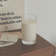 a glass of milk sitting on top of a wooden table