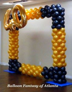 an arch made out of balloons with the letter o on it in black and gold colors