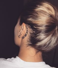 the back of a woman's head with tattoos behind her ear