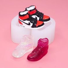 two pairs of shoes sitting on top of a white object in front of a pink background