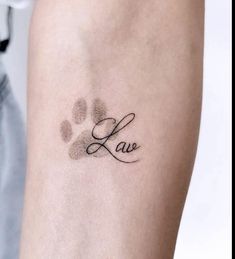 a person with a tattoo on their arm that says love and paw prints in cursive writing