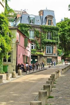 people are sitting on benches in the middle of an alleyway between two large buildings