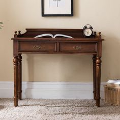 a wooden desk with an open book on it in front of a clock and plant