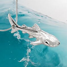 a silver shark ornament floating on top of blue water with a rope attached to it