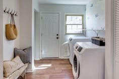 a washer and dryer in a room with wood flooring next to a door