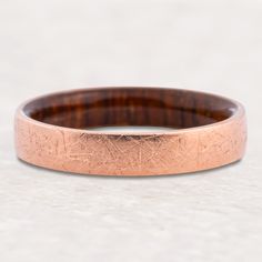 a close up of a wedding ring on a white surface with a wood grain in the center