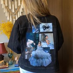 a woman standing in front of a door wearing a black jacket with pictures on it