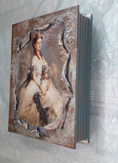 a book with an image of a woman sitting on it's cover is hanging on the wall