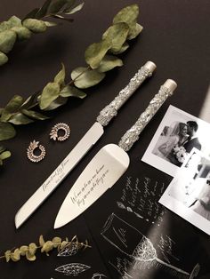 the wedding cake knife is next to some photos and greenery, with an envelope in front of it