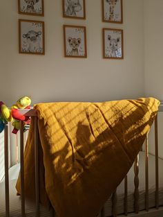 a baby crib with yellow blankets and pictures on the wall