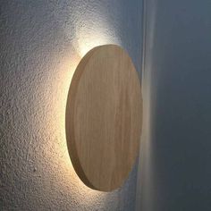 a light that is on the wall next to a white wall with a wooden circle