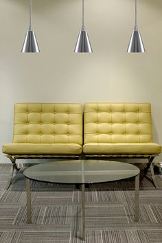 two yellow couches sitting on top of a carpeted floor next to a coffee table