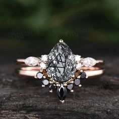 an engagement ring with a pear shaped diamond surrounded by white and black diamonds