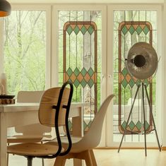 a dining room table with chairs and a fan in front of glass doors that have stained glass panels on them