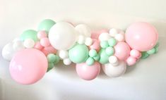 some balloons are hanging on the wall in front of a white background with pastel colors