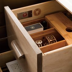 an open drawer in a wooden cabinet filled with watches and other items, including keys