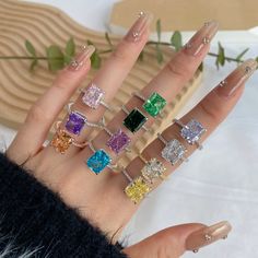 a woman's hand with five different colored rings on it and one is holding the other