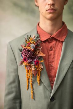 a man in a suit with flowers on his lapel and an orange button up shirt