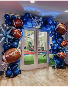 a balloon arch with footballs and stars on it in the middle of a room