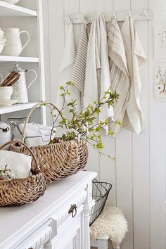 some baskets are sitting on a white shelf next to a wall with towels hanging from it