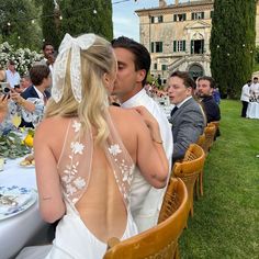 a bride and groom kissing in front of an outdoor dining area with people sitting at tables