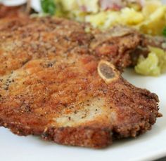 a piece of meat on a white plate with some vegetables in the backgroud