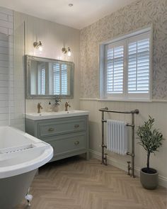 a bath room with a tub a sink and a mirror on the wall next to a window