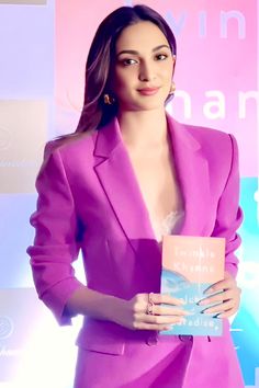 a woman in a pink suit holding a book