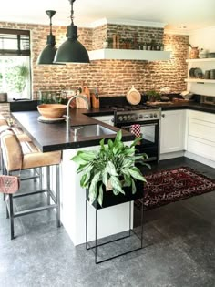 a kitchen with an island, sink and stove top oven next to a brick wall