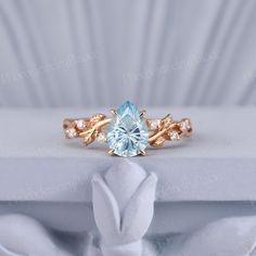 a ring with a blue topazte surrounded by white diamonds on a white cloth