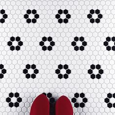 a pair of red shoes sitting on top of a white floor next to black and white tiles