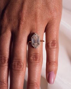 a woman's hand with a diamond ring on her finger and pink manicured nails