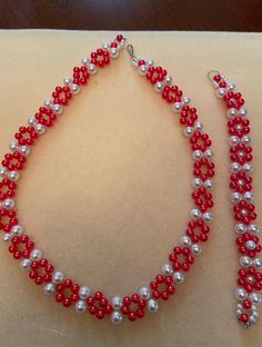 red and white hand beaded necklace and bracelet Red Single Strand Beaded Bracelet, White Heart Beads Jewelry For Party, White Single Strand Beaded Bracelet For Gift, Red Beaded Jewelry For Gifts, Red Jewelry With Colorful Beads For Gift, Elegant Heart Beads For Gifts, Gift Red Jewelry With Colorful Beads, Elegant Red Beaded Jewelry, Red Spacer Beads Jewelry As Gift