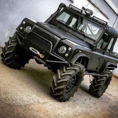 a large black truck parked on top of a cement floor next to a building with windows