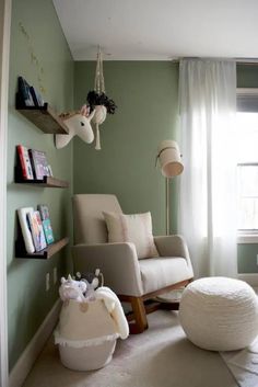 a living room with green walls and white furniture in the corner, including a rocking chair