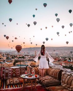 a woman standing on top of a couch in front of hot air balloons