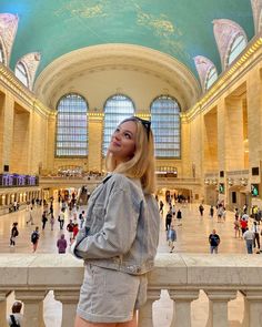 a woman is standing in the middle of a train station