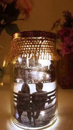 two people are sitting on a bench under a jar with lights in front of them