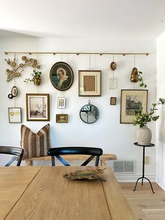 a dining room table with chairs and pictures on the wall above it, along with other decor