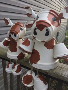 some brown and white cows are hanging on the side of a house with bells attached to them